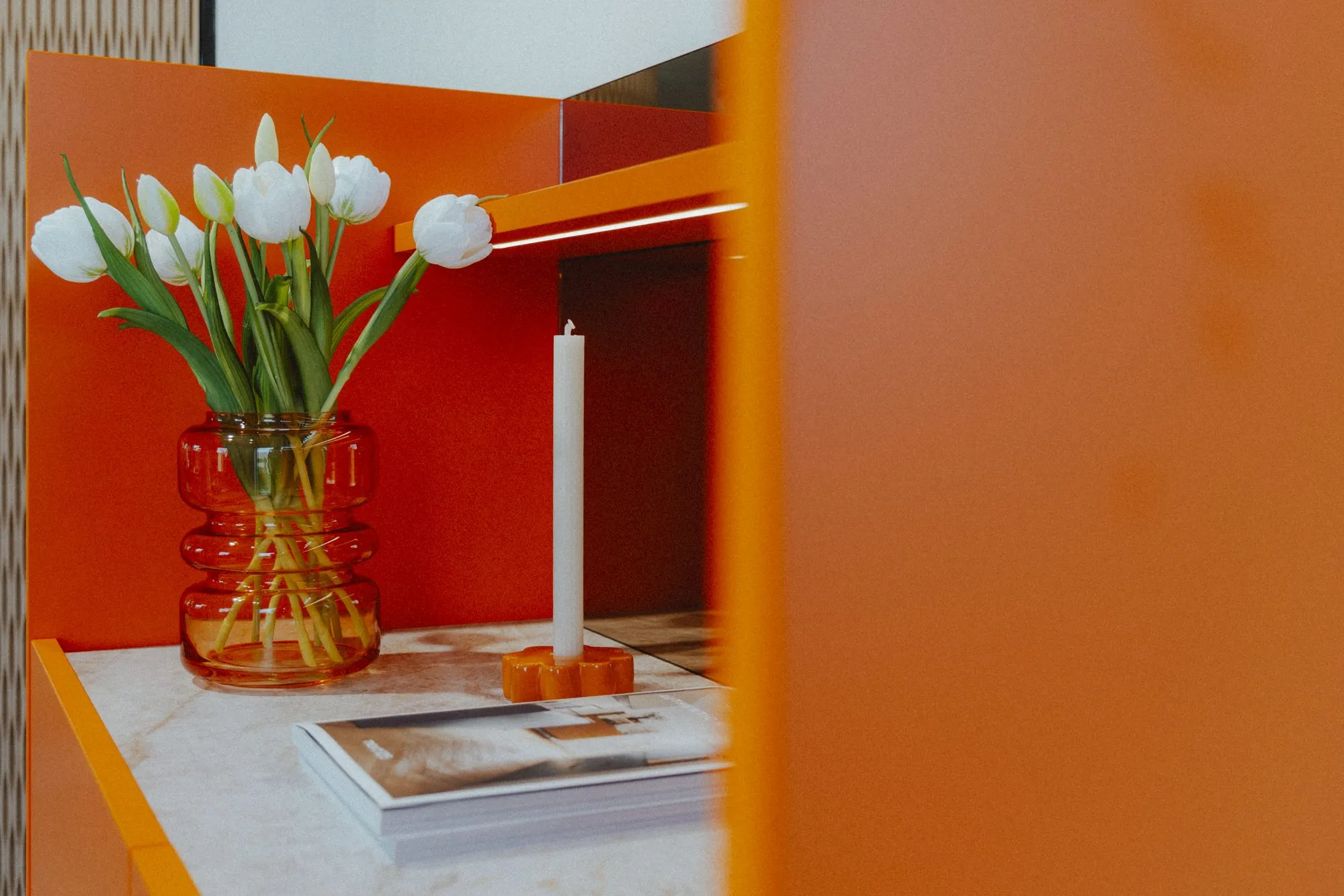 Orangefarbene Nische mit Tulpen und Kerzen